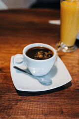 closeup to cup of coffee with cream, saucer on wooden table, hot caffeinated drink as breakfast lifestyle