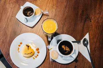 top perspective of food and drinks, details of cake decorated with icing, a cup of coffee and a glass of orange juice, cafeteria in restaurant