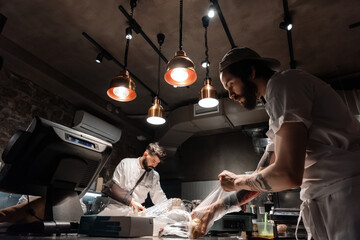 Male cooks unpacking ingredients in restaurant kitchen