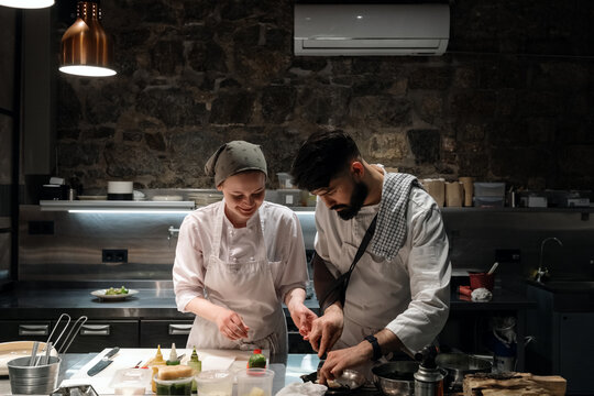 Male and female cooks preparing dish together