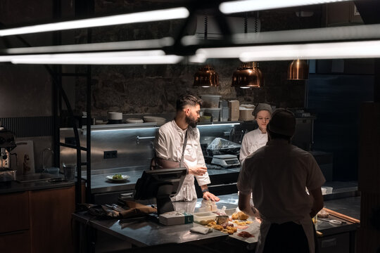 Chef speaking to assistants in restaurant kitchen