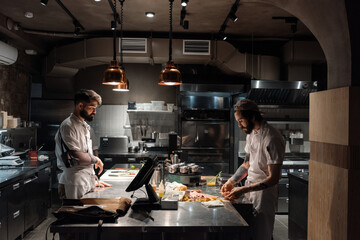 Male chef watching working colleague