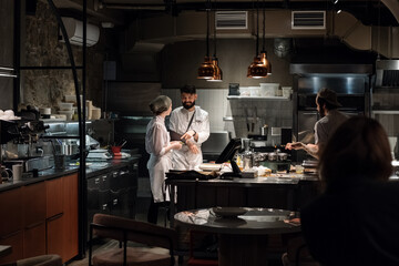 Cooks talking and working in restaurant kitchen