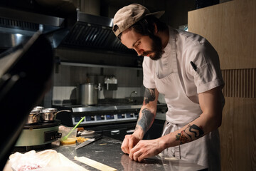 Bearded cook rolling pasta in kitchen
