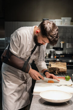 Chef with injured arm cutting fish fillet