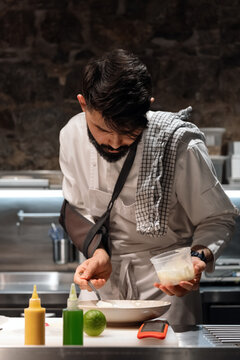 Male cook smearing sauce on plate