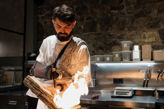 Bearded man burning wood in restaurant kitchen