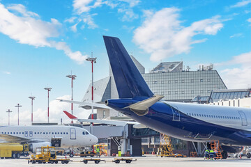 Aircraft in pre-flight maintenance and their tails at the airport next to the passenger terminal.