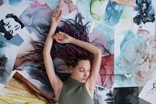 Sensual illustrator lying on abstract paintings