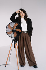 Fototapeta na wymiar Fashion studio photo of stylish European brunette woman in in long baggy pants and a black jacket posing on white background. Trendy office style in clothes.