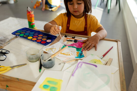 Kid painting with watercolors in playroom
