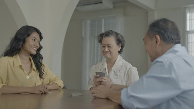 Holiday concept of 4k Resolution. Asian families take turns discarding cards on the table while playing games at home. Family gambling games.