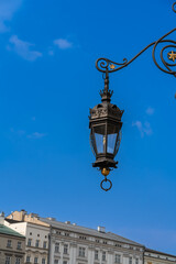 Fototapeta na wymiar Antique street lighting lantern over the houses of the old city against the blue sky