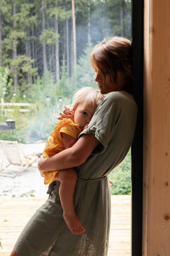 Mother embracing baby in countryside house doorway