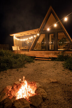 Campfire burning near cottage at night