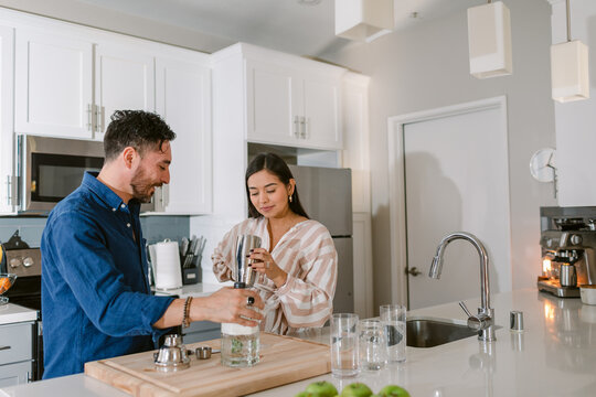 Happy couple preparing drink at kitchen
