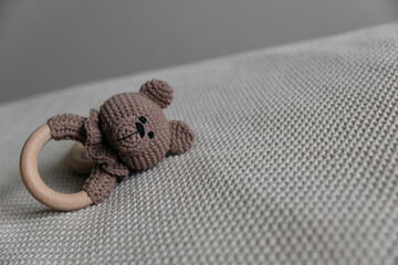 Handmade rattle-rodent toy in the form of a knitted bear in brown color.