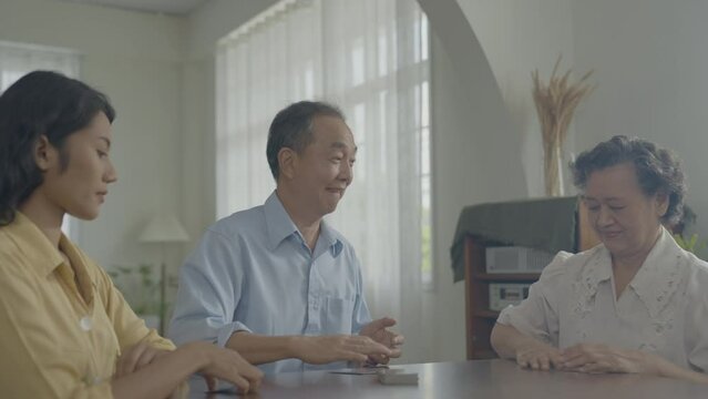 Holiday concept of 4k Resolution. Asian families take turns discarding cards on the table while playing games at home. Family gambling games.