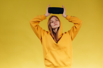 Funny young girl looking, waving hand, holding portable wireless bluetooth music speaker, isolated...