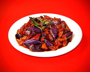 Purple Eggplant and tofu with Chinese basil, on a red cloth background.