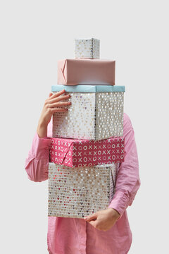Woman holding stack of gift boxes over grey background