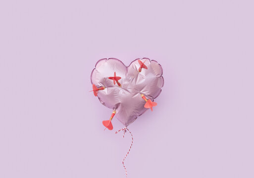 Heart shaped balloon pierced by dart arrows