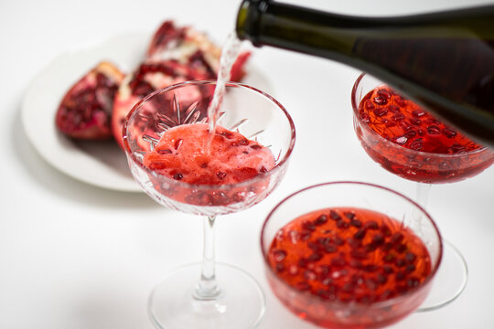 Pouring champagne making pomegranate Mimosa cocktail