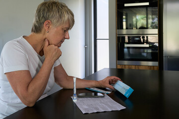 Woman reading box of Covid RAT kit