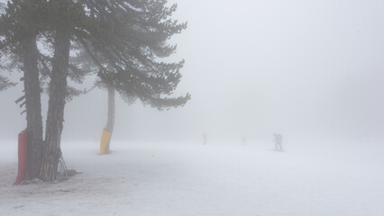 Silhouette of a cross country skier barely visible in very dense fog. Bad weather on ski resort