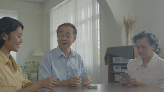Holiday concept of 4k Resolution. Asian families take turns discarding cards on the table while playing games at home. Family gambling games.