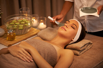 Luxurious expert hands. A young woman lying in a day spa with a face mask being applied.