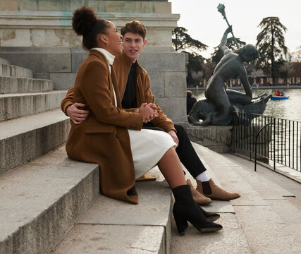 Multiracial couple sitting at a park stairs