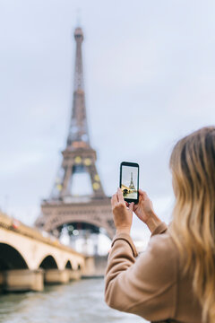 Anonymous woman photographing Eiffel Tower