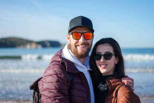 Happy traveling couple hugging on ocean coastline