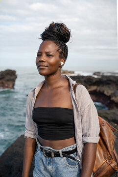Black Self-aware empowered  woman squinting at the ocean 