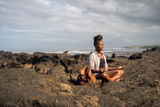 Self-aware empowered Woman meditating at rocky area