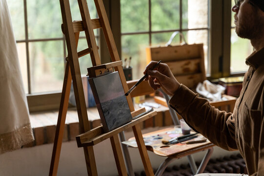 man painting a canvas at home