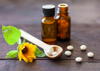 Wooden spoon of homeopathic pills, bottles and a flower. Natural medicine