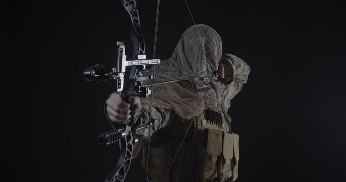 Silent killer - an archer in a military uniform and a futuristic mask takes aim and makes a shot. Modern warfare and special operations concept.