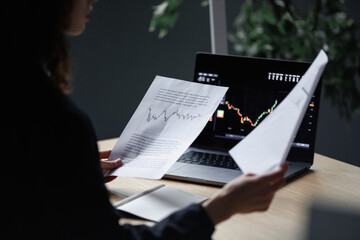 broker analyzing financial chart on laptop and document