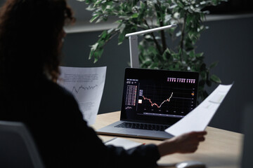 Faceless woman reading financial reports 