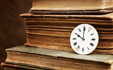 Old books and vintage antique clock face. Story time, storytelling, past background.