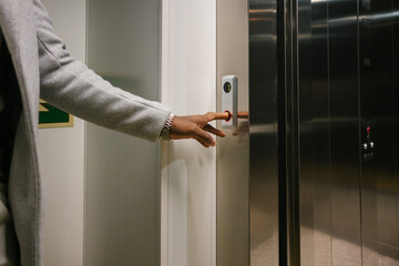 Crop person calling elevator with opening doors