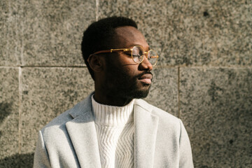 Calm black guy with closed eyes standing on city street