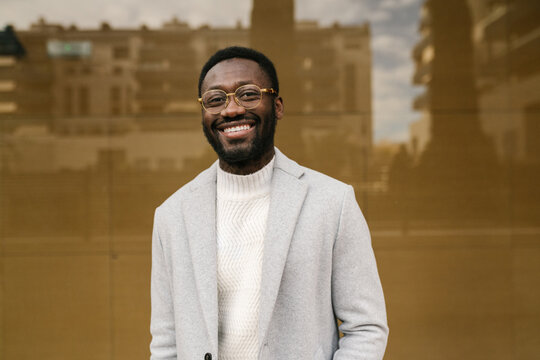 Cheerful elegant black male smiling at camera on street