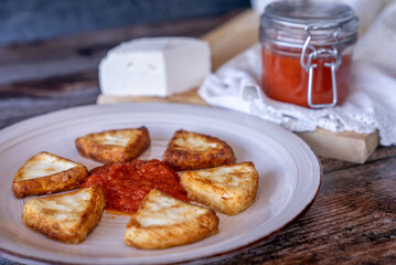 Fried goat cheese with tomato, a typical dish from the Region of Murcia, Spain, on a wooden background.