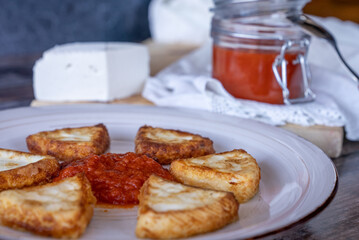 Fried goat cheese with tomato, a typical dish from the Region of Murcia, Spain, on a wooden background.