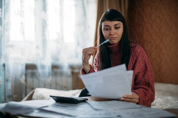 Sad woman holding utility bills in her hands. The concept of rising prices for heating, gas,...