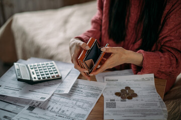 Close-up of woman's hands with empty wallet and utility bills. The concept of rising prices for...