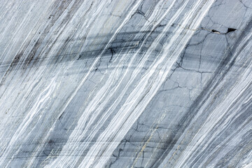 Surface of a cut of gray Karelian marble rock in Ruskeala in Karelia, for use as an abstract background and texture.